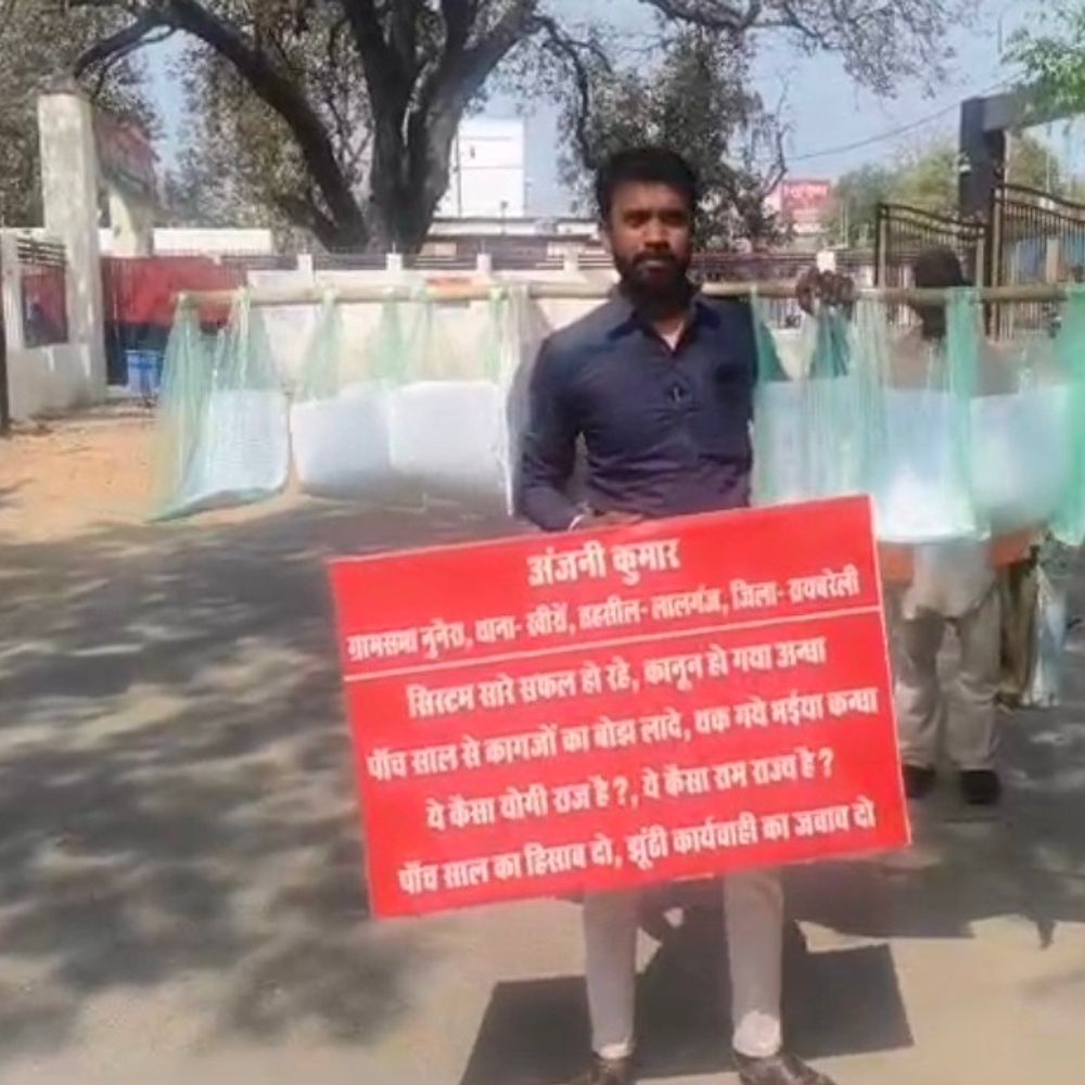 बोरी का बैग, तख्ती लेकर प्रदर्शन कर रहा युवक:रायबरेली के ग्राम सभा में भ्रष्टाचार के खिलाफ 5 साल से अधिकारियों के चक्कर लगा रहा