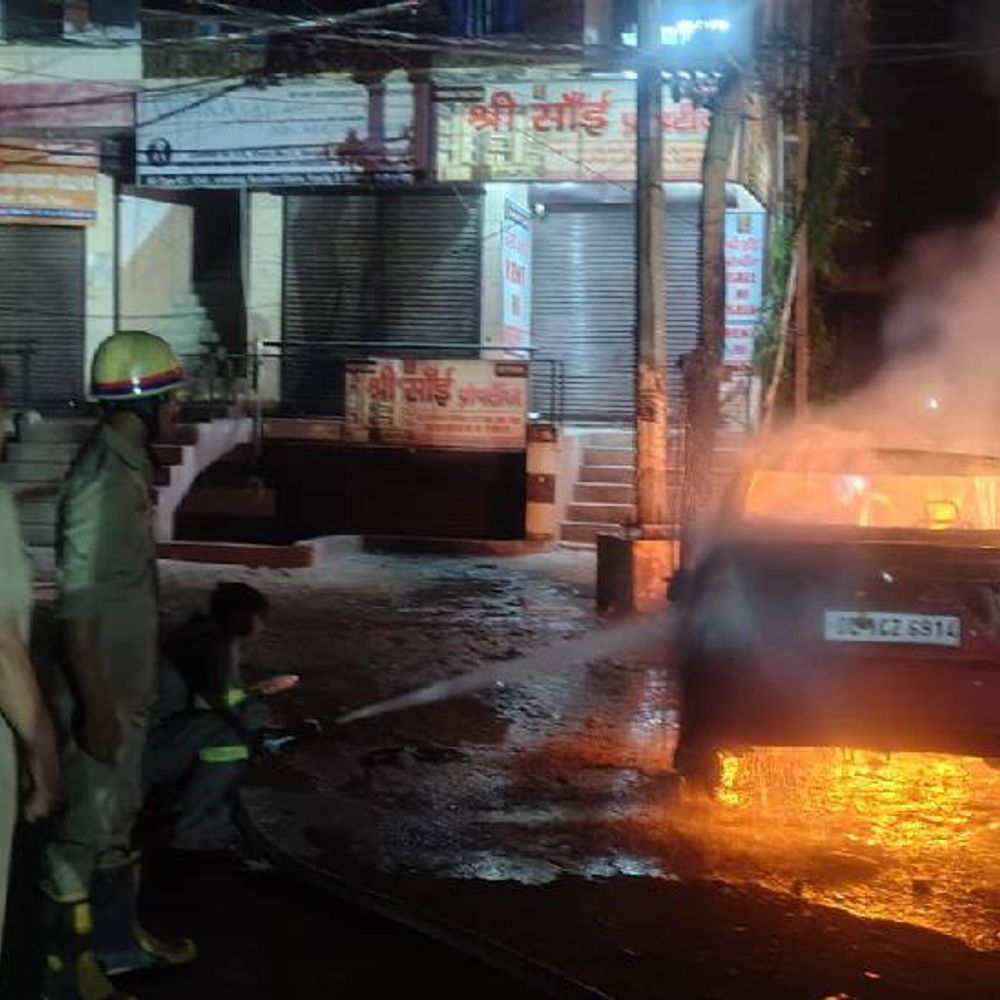 नोएडा अजनारा होम्स के पास कार में लगी आग:बिजली के खंबे के नीचे खड़ी थी, वायर गिरने से लगी आग, 30 मिनट में पाया काबू