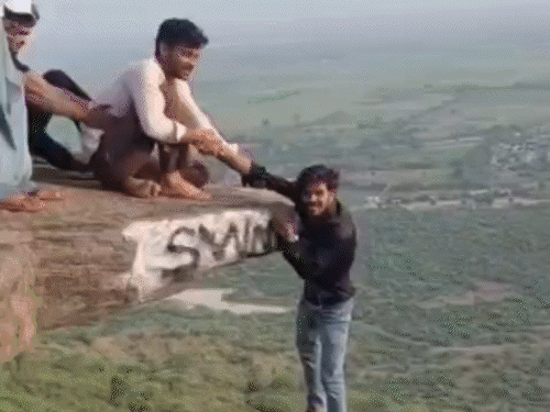 रील बनाने के लिए पहाड़ी से लटका युवक:दोस्तों ने एक हाथ से पकड़ा, दूसरे हाथ से विक्ट्री साइन बनाया; पुशअप्स भी किए