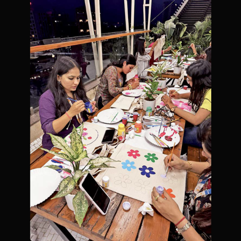 કોર્પોરેટ કર્મચારીઓ માટે પેઇન્ટિંગ WORKSHOP: ક્રિએટિવ બ્રેક, જેમાં ટ્રે અને ટોટ બેગ પર ફૂલ બનાવી રંગો પૂરવામાં આવ્યા.
