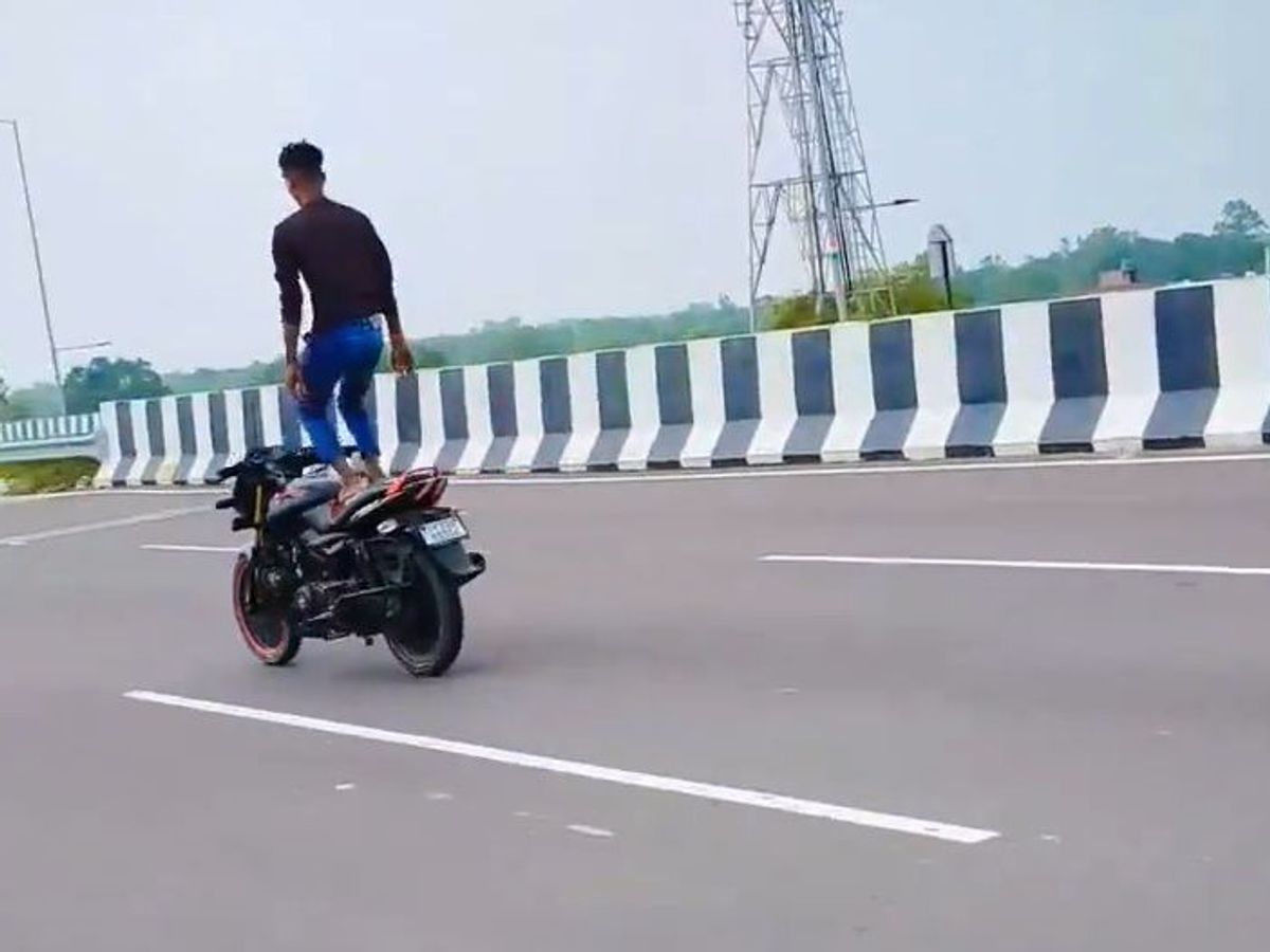 A young man performing dangerous stunts on a moving bike