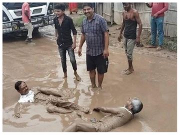 सड़क में बने गड्ढों में डुबकी लगाते लोग। - Dainik Bhaskar