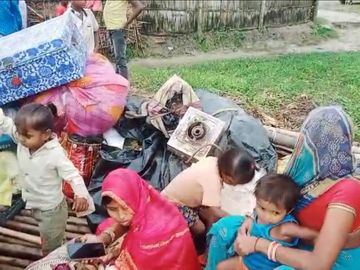 पानी बढ़ने के बाद परिवार और घर के सामान के साथ खुले में बैठी महिला। - Dainik Bhaskar