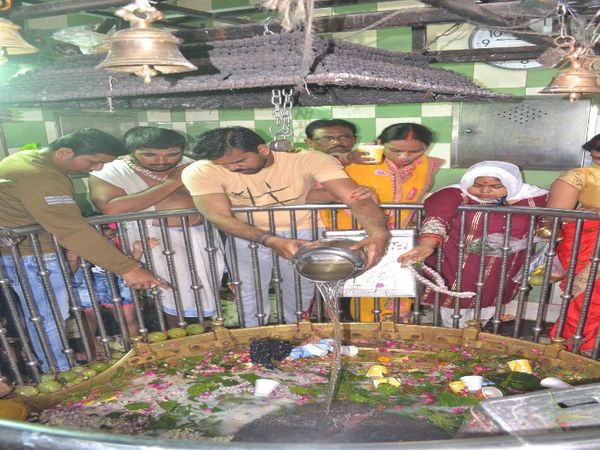 गौरी केदारेश्वर मंदिर में अरघे के ऊपर से जलाभिषेक करते श्रद्धालु।