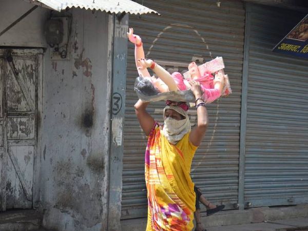 लॉकडाउन के चलते नहीं बिकी होलिका की मूर्ति तो मायूस होकर ले जाते हुए महिला कारीगर।