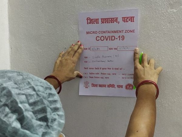 पटना के एक माइक्रो कंटेनमेंट जोन में पोस्टर चिपकाता स्वास्थ्यकर्मी। - Dainik Bhaskar