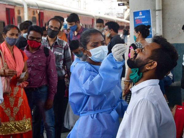 मुंबई के दादर रेलवे स्टेशन पर यात्रियों के स्वाब का नमूना लेती हुई BMC की एक महिला कर्मचारी।