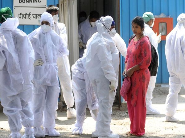 मुंबई के जंबो कोविड सेंटर के बाहर अपनी शिफ्ट से पहले PPE किट पहनकर तैयार होते BMC के स्वास्थ्यकर्मी।