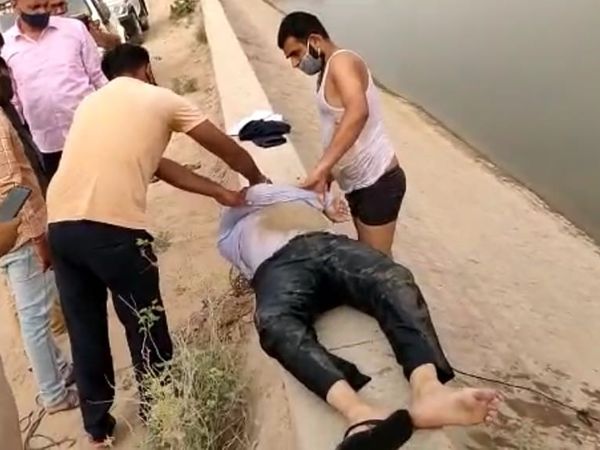 युवक को बाहर निकालकर बचाने की कोशिश करते स्थानीय तैराक। - Dainik Bhaskar