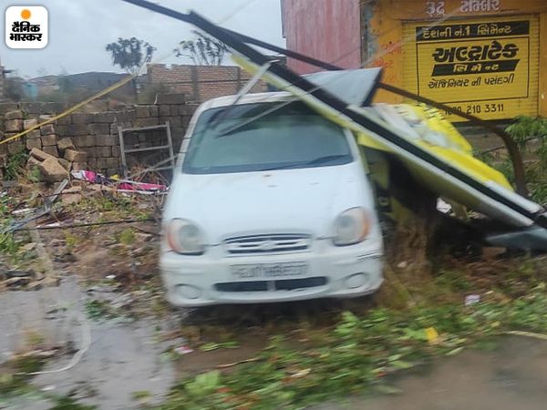 Electricity supply came to a standstill due to falling of the poles. Trees scattered like straw in the streets | तूफान का खौफनाक मंजर; तेज हवाओं के बीच खंबे गिरने से कई इलाकों में बिजली सप्लाई ठप, सड़कों पर गिरे पेड़ों ने रोके रास्ते 4 यह तस्वीर भी उना की है। यहां तेज हवाओं से दुकान के होर्डिंग्स उड़कर पास में खड़ी कार के पास जाकर गिर गए। इसमें आसपास के छप्पर भी उखड़े हुए दिख रहे हैं।