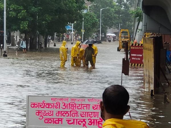मुंबई के हिंदमाता इलाके में सड़क पर जमा पानी को हटाने का प्रयास करते BMC के कर्मचारी।
