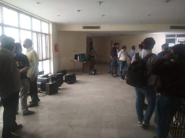 ऑफिस खाली करने के बाद बाहर पड़े कम्प्यूटर और वहां काम करने वाले कर्मचारी।