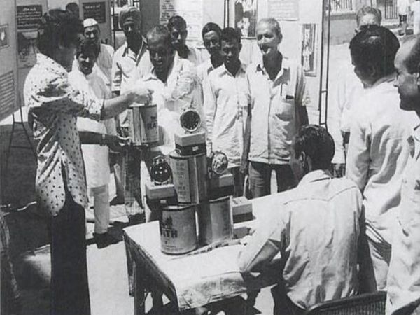 एक नसबंदी कैंप के बाहर नसबंदी कराने आए पुरुषों को घी का डिब्बा और घड़ी देते हुए कर्मचारी।