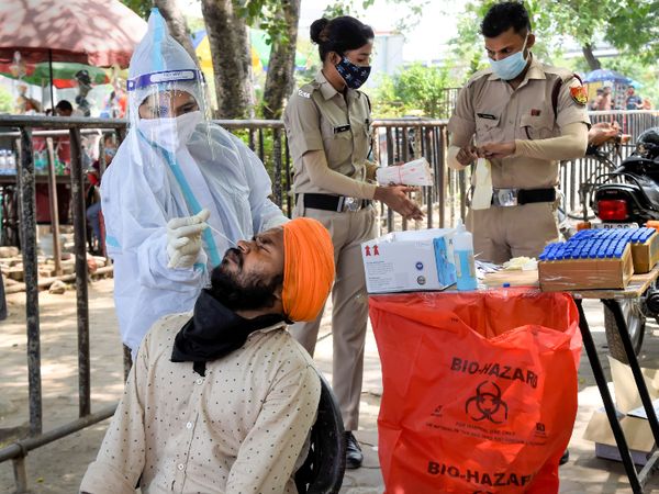 यह फोटो नई दिल्ली की है। यहां कोविड टेस्टिंग सेंटर पर कोरोना की जांच के लिए स्वाब का नमूना लेते हेल्थकेयर वर्कर। - Dainik Bhaskar