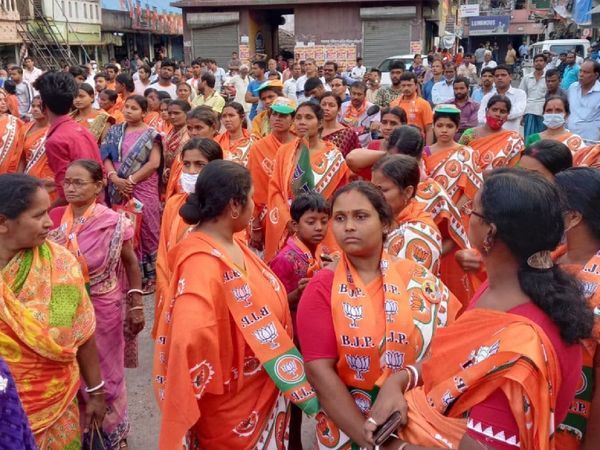 भाजपा के लोगो के साथ भगवा साड़ी पहने महिलाएं।