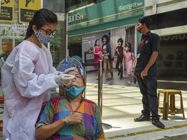 मुंबई के एक मॉल के बाहर परीक्षण के लिए नमूना लेते बीएमसी स्वास्थ्य कार्यकर्ता।