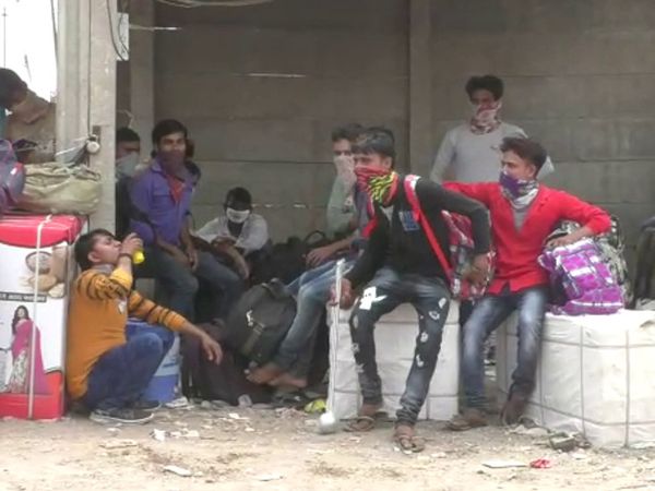 ભર તડકામાં બસની રાહ જોતા શ્રમિકો.