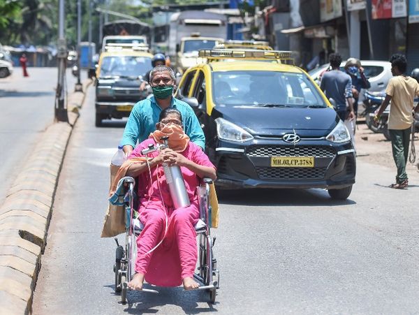 मुंबई के धारावी में एक शख्स अपनी पत्नी को व्हील चेयर पर बैठा कर हॉस्पिटल तक ले जाता हुआ।