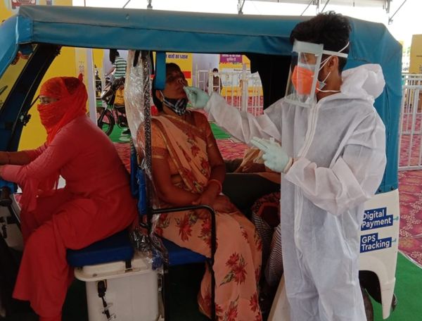 ऑटो रिक्शा में बैठकर सैंपल देती महिला।