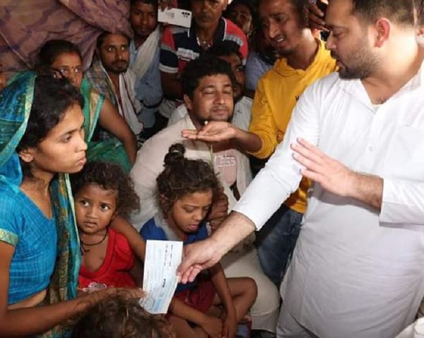 पीड़ित परिजन को चेक देते तेजस्वी।