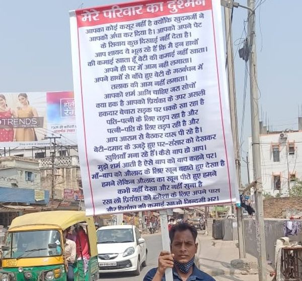 सास-ससुर की प्रताड़ना के बारे में पोस्टर पर लिखकर प्रदर्शन करता युवक।