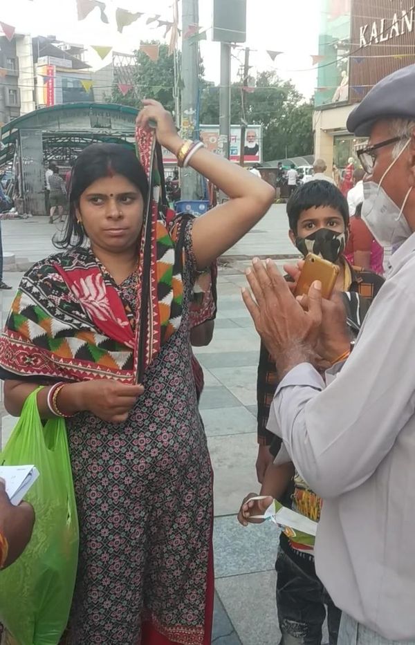 न्यू मार्केट में बिना मास्क के घूम रही महिला के हाथ जोड़कर मास्क पहनने का निवेदन करते नगर निगम के कर्मचारी।