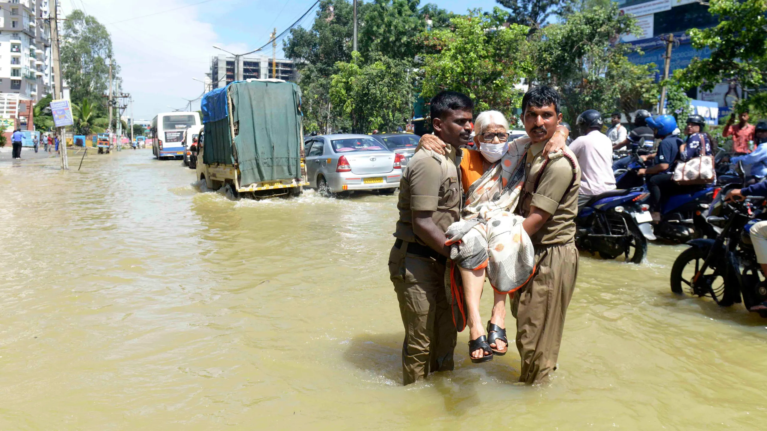 Firefighters help an elderly woman move to a safer area after heavy rainfall in Bengaluru.