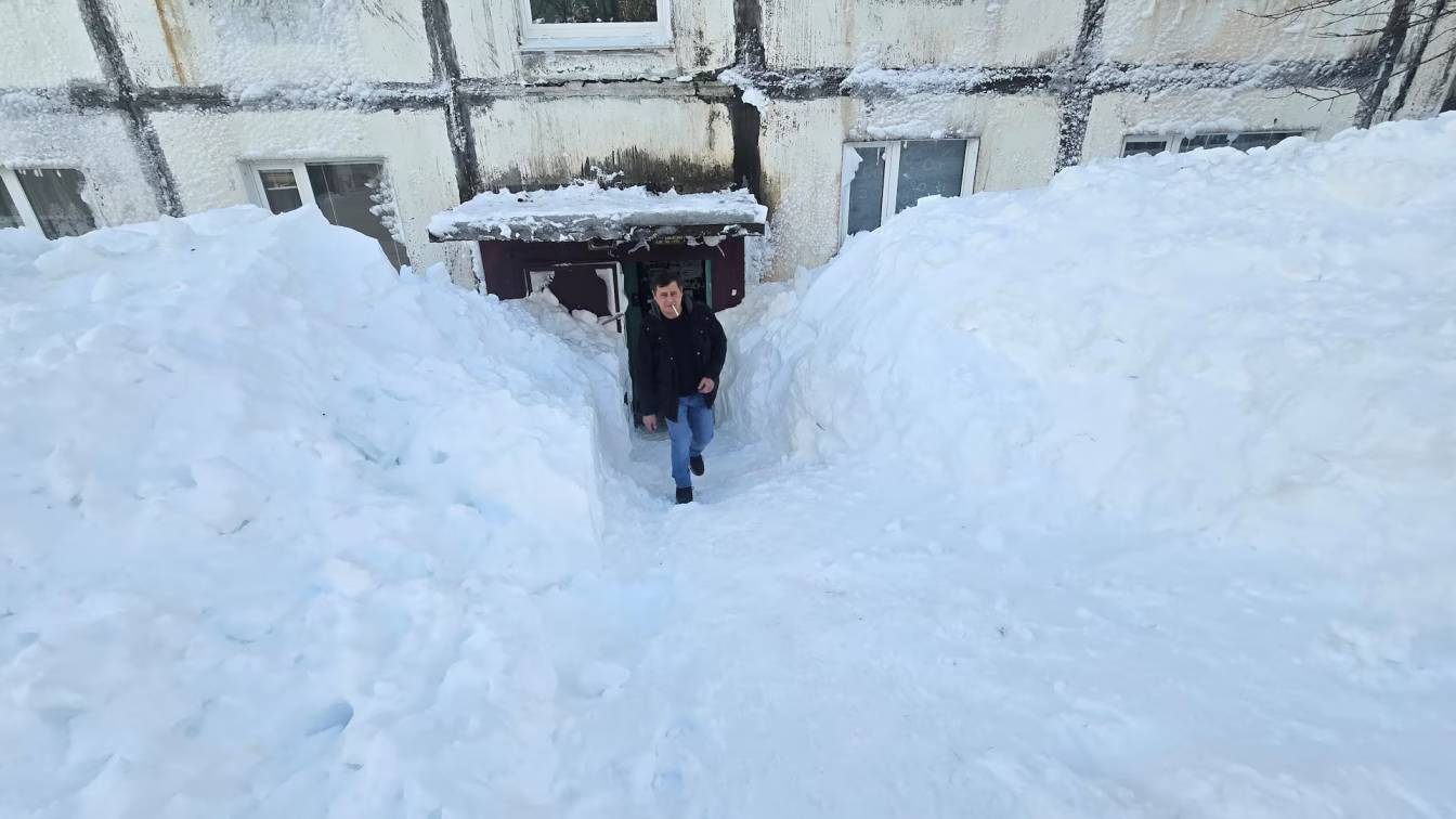 Man walks through towering snowdrifts outside an apartment block after extreme snowstorm hits Petropavlovsk-Kamchatskiy ( Image: Reuters)