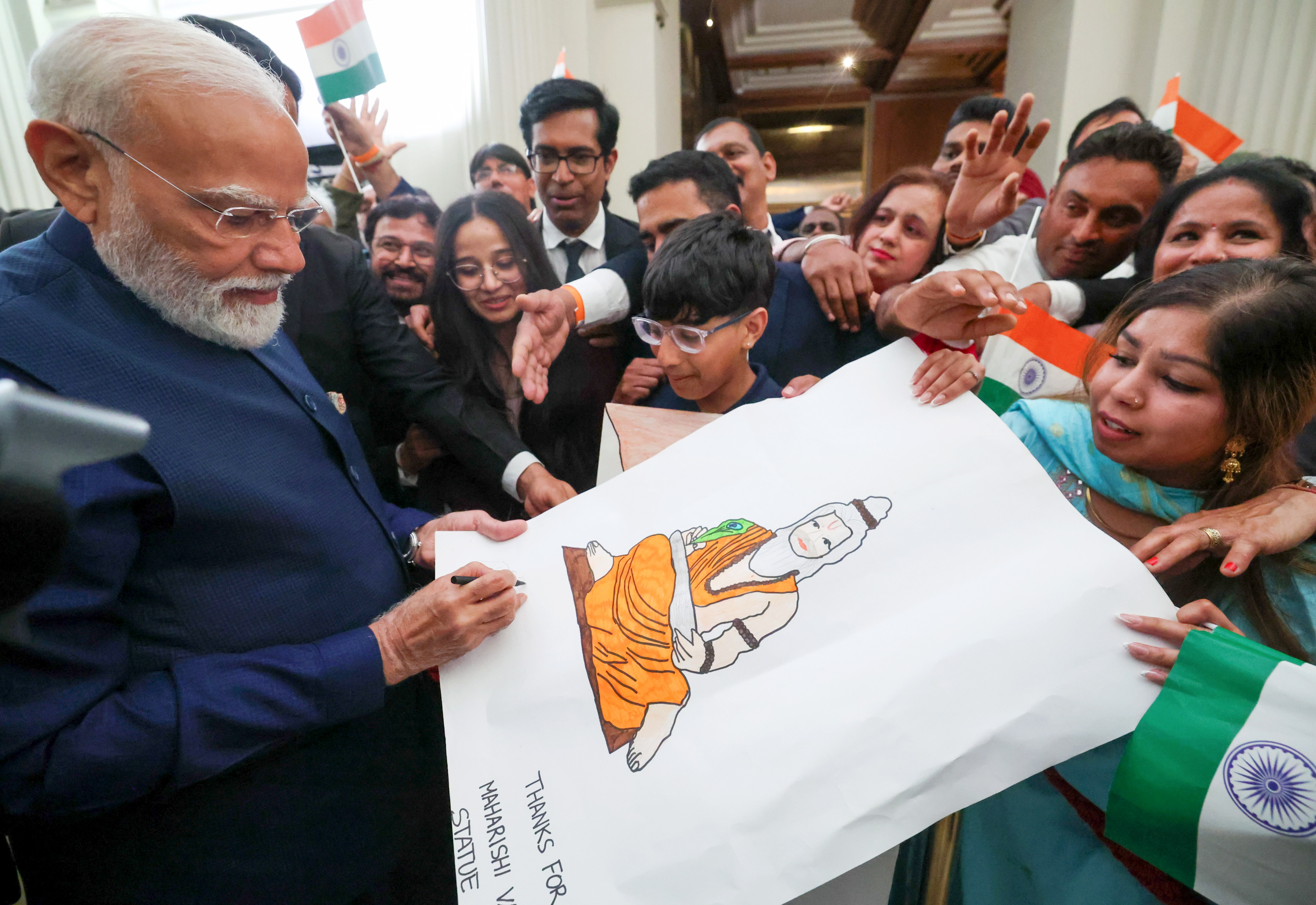 PM Modi autographs a painting during his meeting with Indian expatriates.