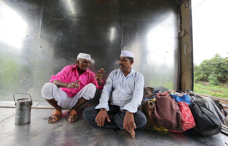 डब्बावाला, जिन्हें टिफिन वाहक के रूप में भी जाना जाता है, पारंपरिक टोपी पहने हुए, 19 सितंबर, 2018 को मुंबई, भारत में एक ट्रेन में यात्रा करते हैं। (छवि स्रोत: रॉयटर्स)