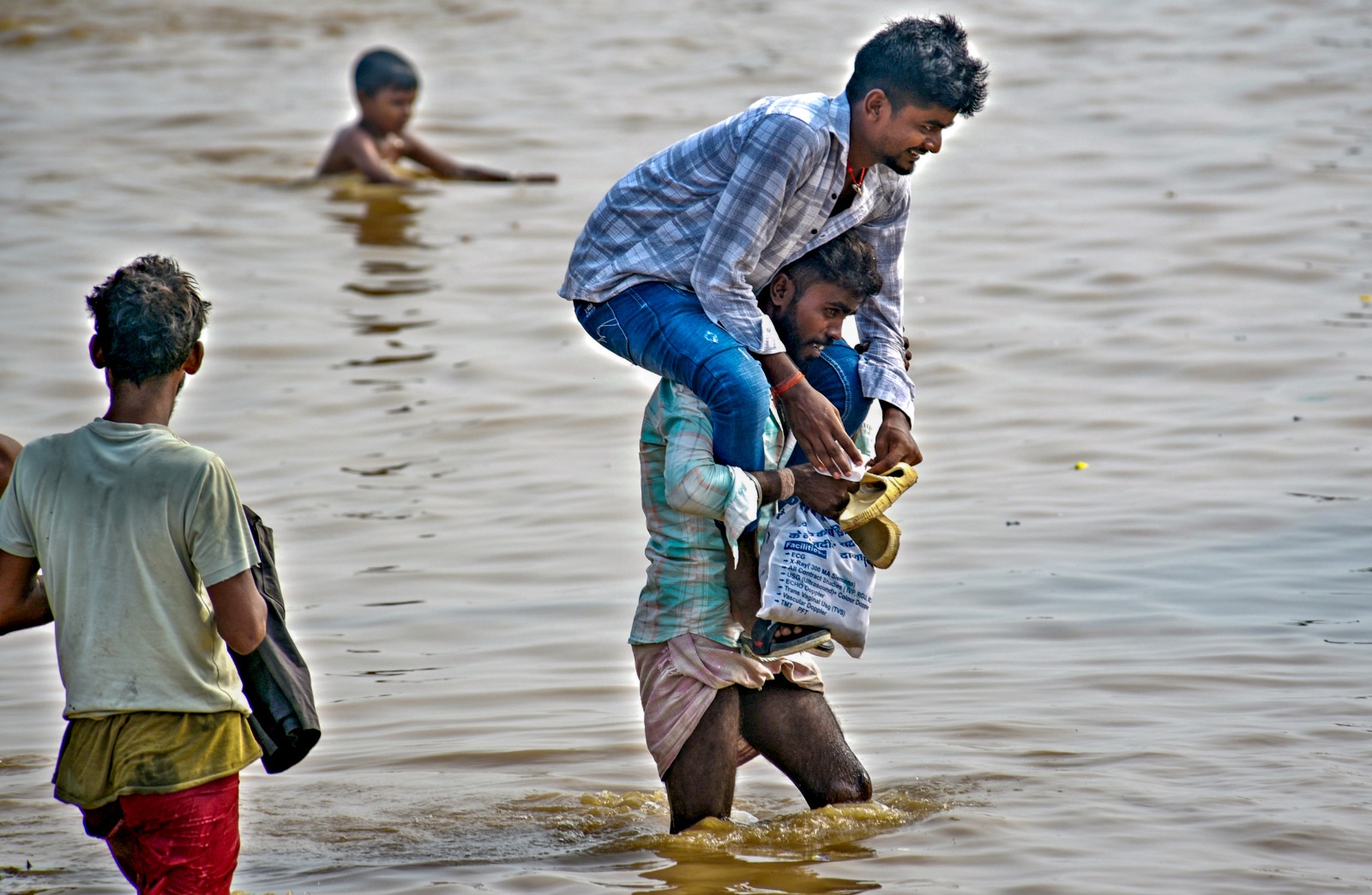 'Carrying hope': Man wades through floodwaters with another on his shoulders in Patna. Photo: PTI
