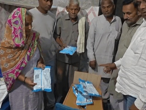 Helper Naresh Kumari shows the packets to the councillor's representative and others who arrived for the inspection.