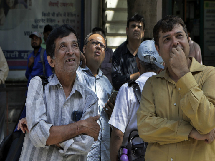 मुंबई में सेंसेक्स के डिस्प्ले बोर्ड को सड़क से निहारते लोग।