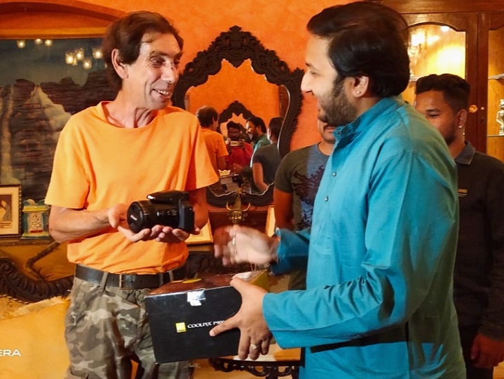 विदेशी पर्यटक को कैमरा देने पूर्व राजपरिवार के सदस्य कमल भंजदेव। - Dainik Bhaskar