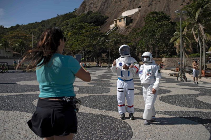 Unique Way To Avoid Coronavirus: Brazilian Couple Wear Spacesuits, People Take Photos And Selfies | स्पेस सूट में ब्राजील का यह कपल वॉक करने निकलता है, लोग फोटो और सेल्फी लेने के लिए पीछे पड़ जाते हैं 2