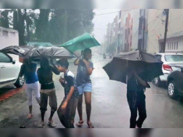 जोरदार बारिश शुरू हुई तो बच्चे और बड़े भी मस्ती के मूड में आ गए। छाता लेकर निकल पड़े।