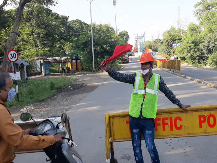मेट्रो प्रोजेक्ट के कर्मचारी ट्रैफिक डायवर्ट करने में मदद कर रहे हैं।
