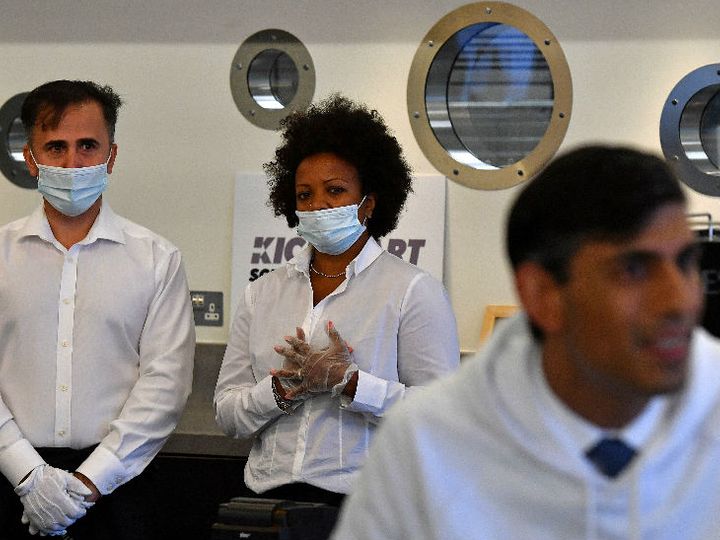 ब्रिटेन में सरकार की नई एंप्लॉयमेंट स्कीम को लॉन्च करने के दौरान वित्त मंत्री को देखते कैटरिंग स्टॉफ। वित्त मंत्री इस दौरान बिना मास्क नजर आए थे।
