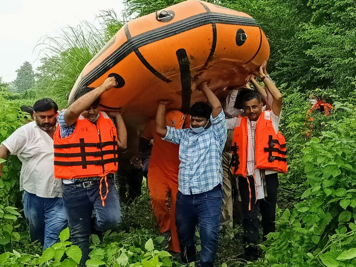 नाव को सिर पर उठाकर आगे बढ़ते डीएम (दाएं से पहले) और अन्य।