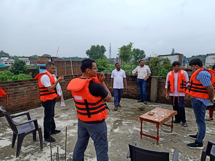 ग्रामीण की छत पर चर्चा करते अफसर।