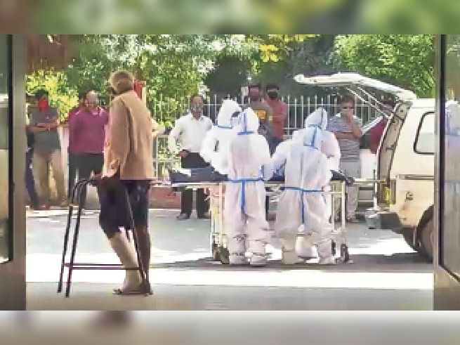 संक्रमित शव को एंबुलेंस में रखने के दौरान भी लोग पास में ही खड़े रहे।