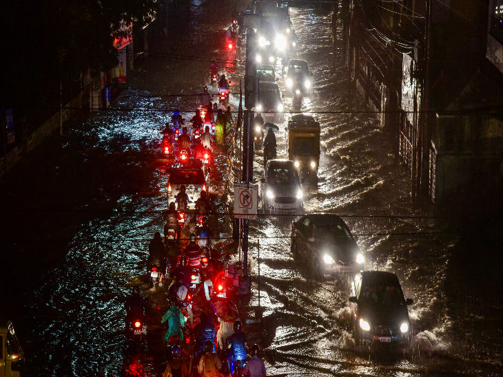 शनिवार रात हुई भारी बारिश के बाद हैदराबाद की पानी से भरी एक सड़क से गुजरती गाड़ियां।