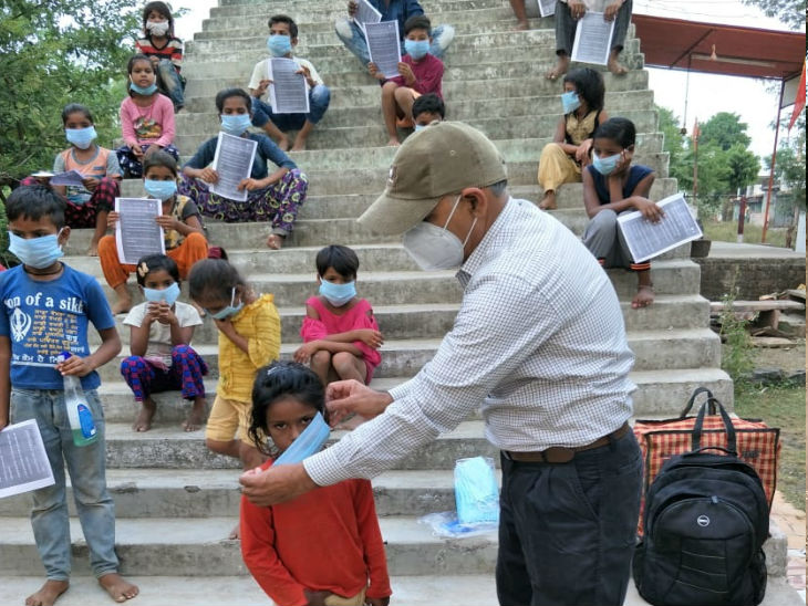 मोहल्ला क्लास के दौरान बच्चे को मास्क पहनाते उमाकांत दुबे।