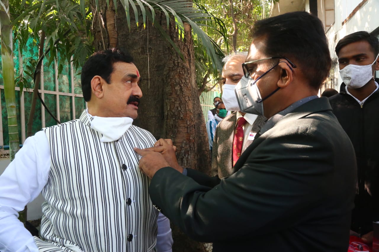 सैनिक कल्याण संचालनालय के संयुक्त संचालक (सेवानिवृत्त) कमांडर उदय सिंह गृहमंत्री नरोत्तम मिश्रा को लैपल पिन और फ्लैग लगाते हुए।