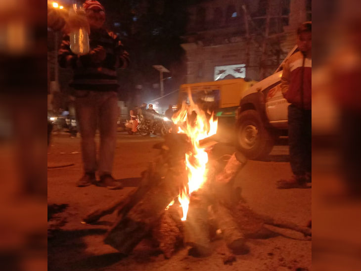 कड़ाके की ठंड के बीच नगर निगम द्वारा जलाए गए अलाव से सहारा लेते लोग।