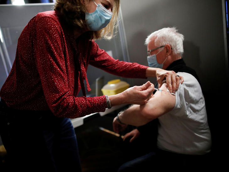 फ्रांस में लोगों को फाइजर वैक्सीन का टीका लगाया जा रहा है। मंगलवार को पेरिस में एक सीनियर सिटीजन को वैक्सीन लगाती हेल्थकेयर वर्कर।