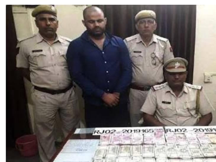 ये पहली तस्वीर 6 सितम्बर की है। जब पपला 32 लाख रुपए के साथ बहरोड़ में पकड़ा गया था। बहरोड़ पुलिस के अधिकारी व उनके बीच में पपला और सामने पकड़ी गई रकम।