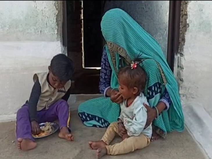 घर की दहलीज पर बैठकर दोनों बेटियों को बाटियां खिलाती जयंती बाई।