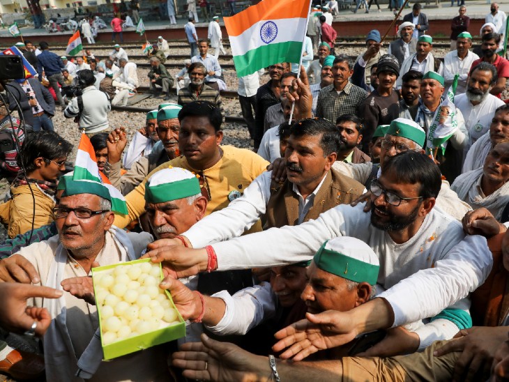 मोदी नगर रेलवे स्टेशन पर पुलिसकर्मियों को मिठाई ऑफर करते हुए किसान।