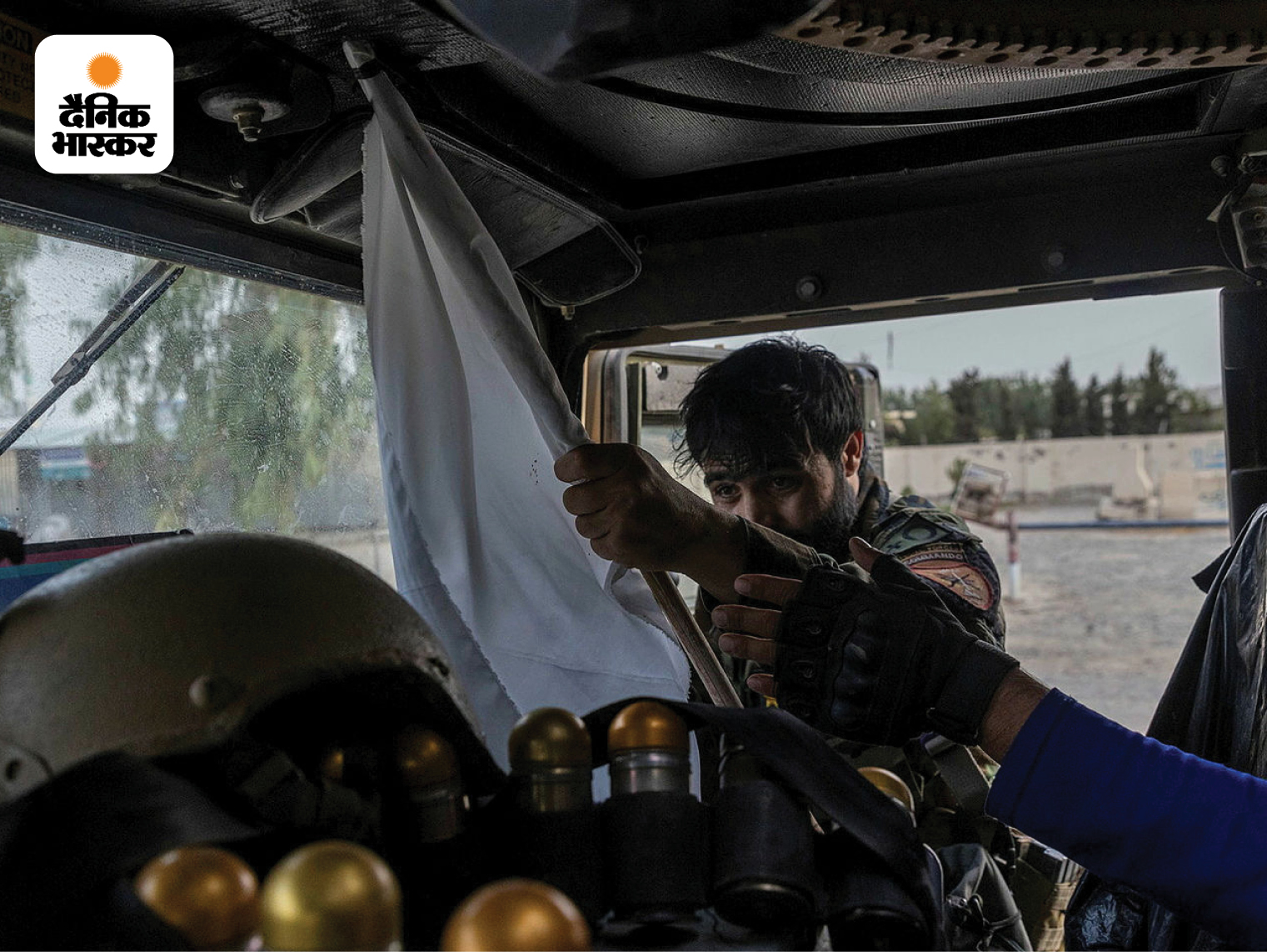 कंधार में अमेरिका के दिए हमवी सैन्य बख्तरबंद वाहन के भीतर की इस तस्वीर में अफगान पुलिस का एक जवान सफेद झंडा लिए दिख रहा है। इस जवान को अफगान सेना का एक दस्ता तालिबान की घेराबंदी से निकालकर लाया था।